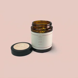 عبوة زجاجية بنية اللون من دخون 2 لماركة اليريا موضوعة على خلفية وردية فاتحة مع الغطاء الأسود بجانبها.